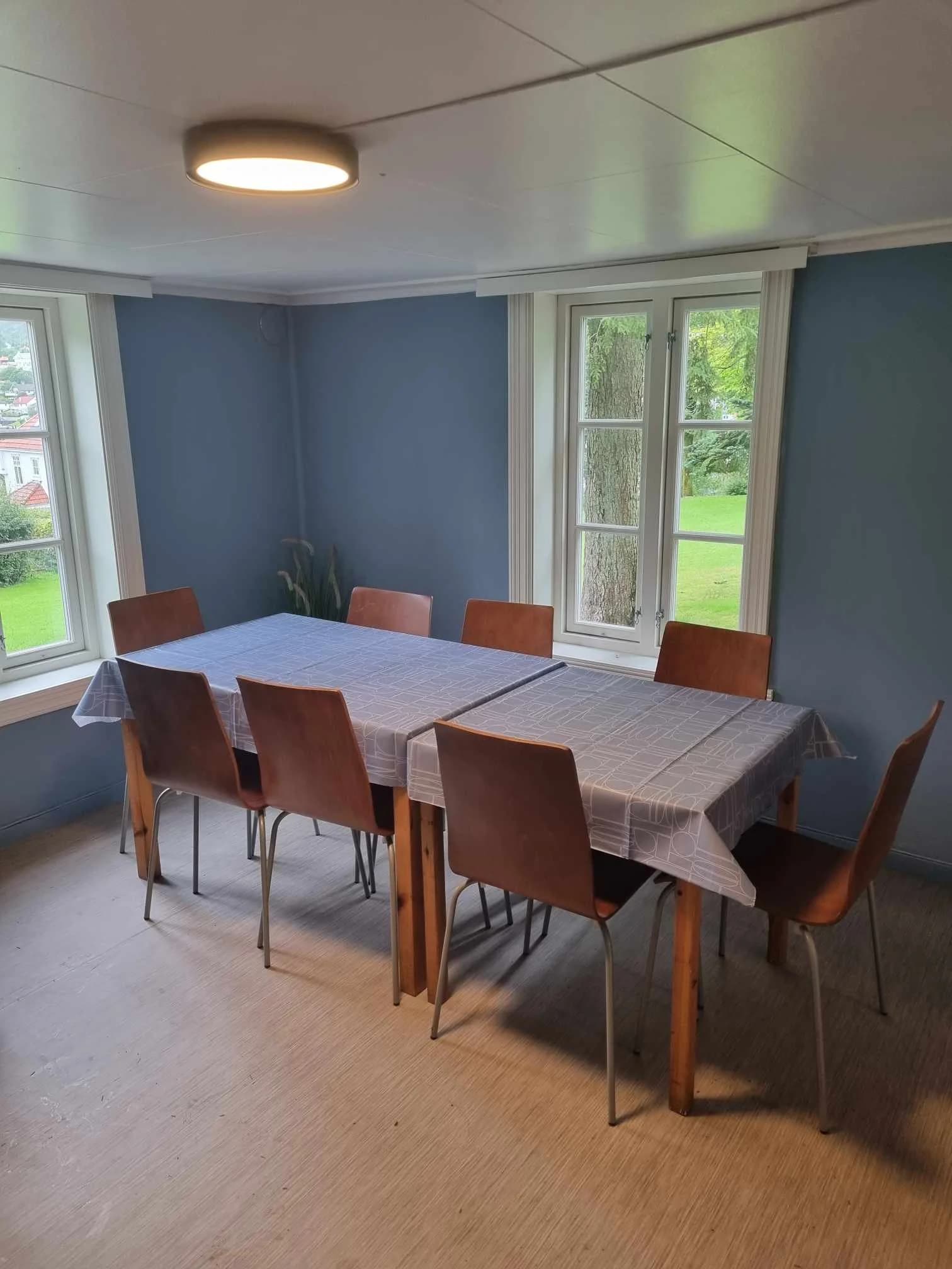 Lys stue med spisebord og store vinduer